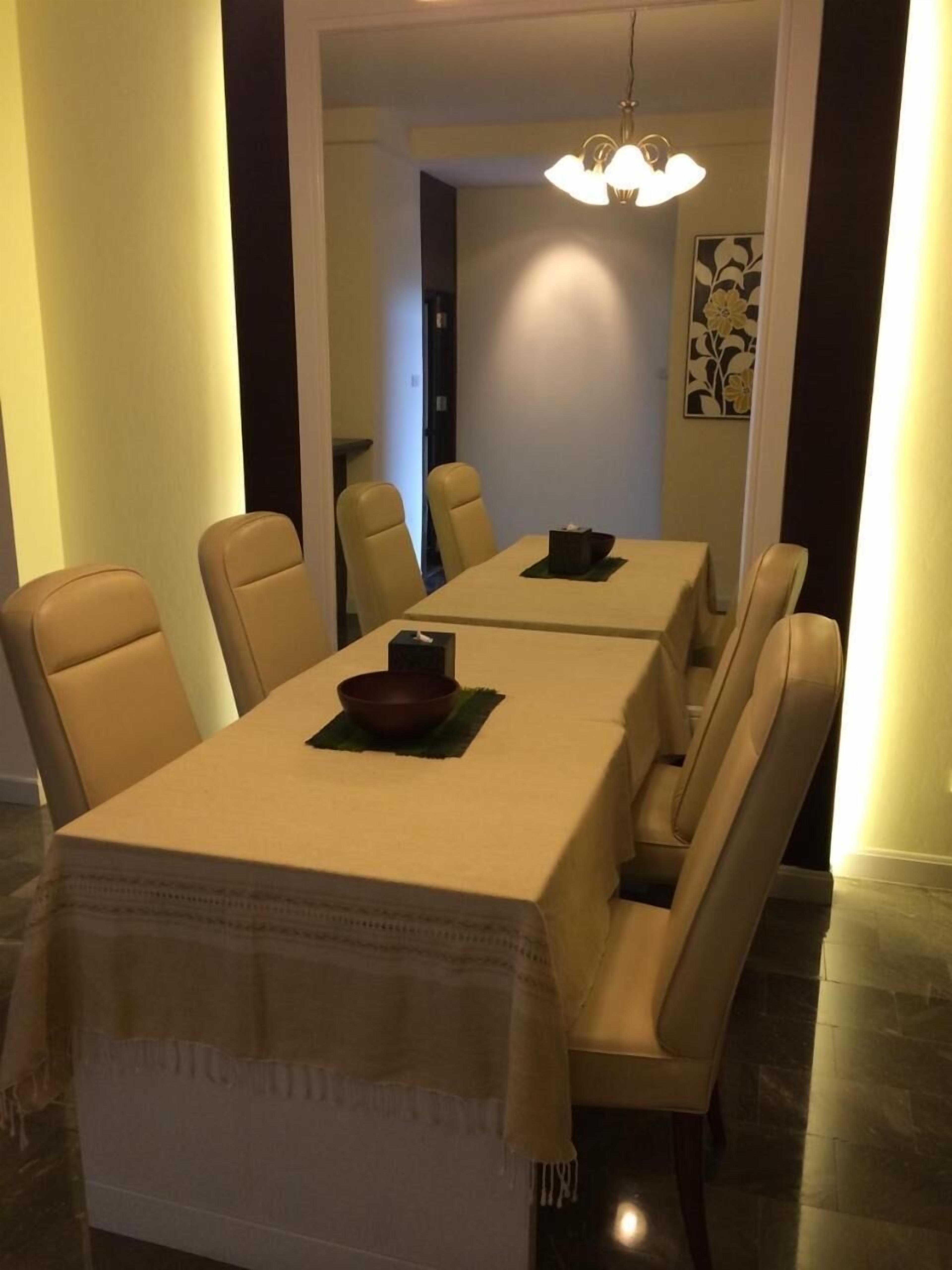 A dining area with a long table and six chairs, a small table with a bowl, and a hanging light fixture.
