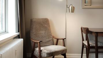 Une pièce avec un radiateur, une chaise, une table et un lampadaire.