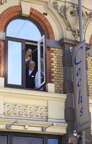 A building facade with a large arched window, a sign reading "Cochs Pensionat," and a decorative stone relief. - Cochs Pensjonat (Oslo)