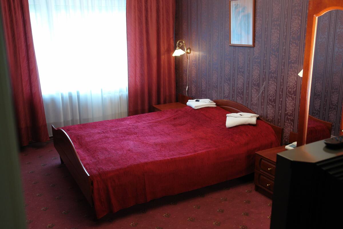 Ein Hotelzimmer mit einem großen Bett, einem Nachttisch, einem Schreibtisch und einer Lampe.