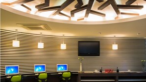 Una oficina moderna con tres escritorios, cada uno con un monitor de computadora, sillas ergonómicas y un televisor de pantalla plana montado en la pared.
