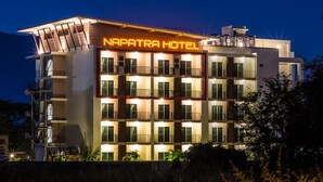 Un hotel de varios pisos con balcones y un cartel que dice "NAPATRA HOTEL".