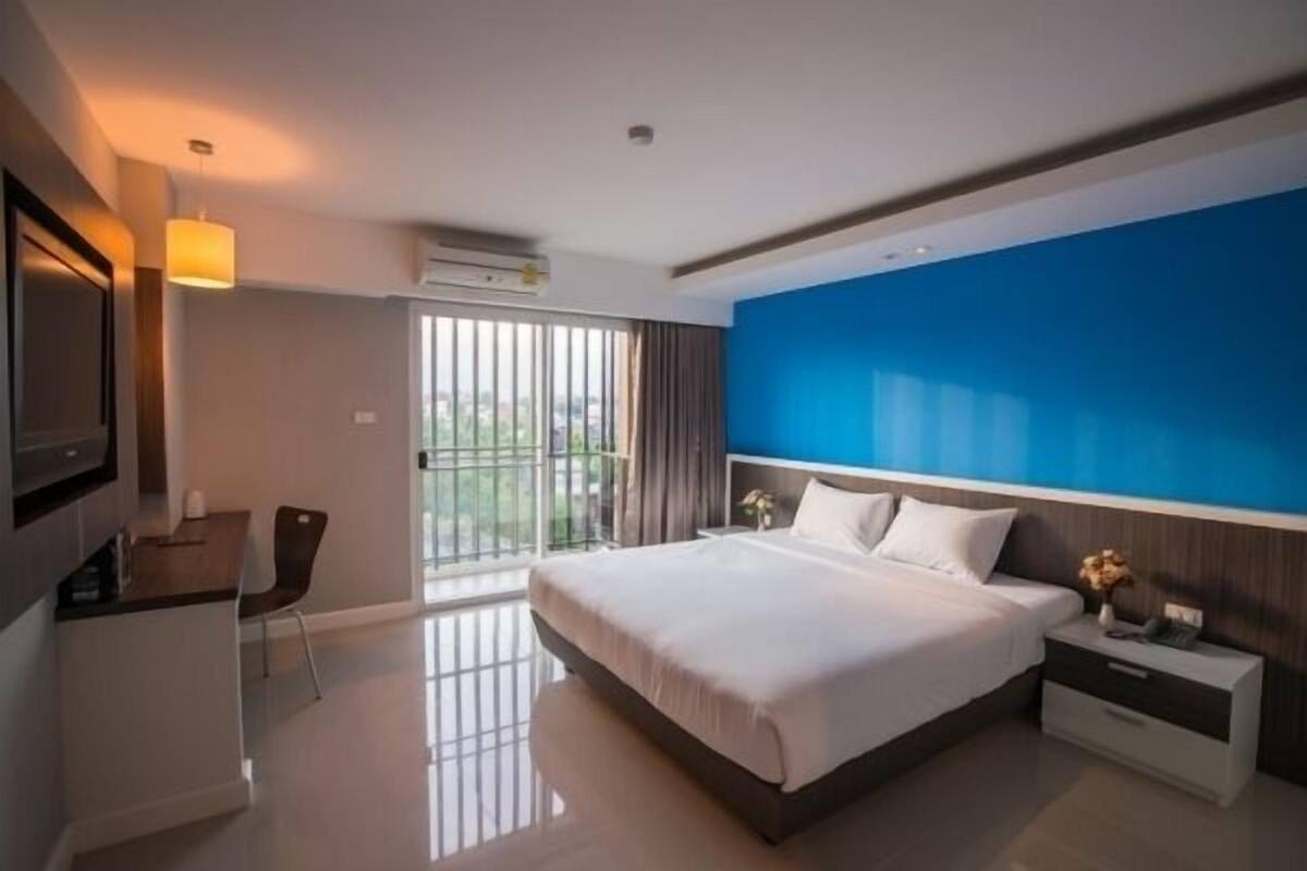 A modern hotel room with a large bed, a desk, and a TV.