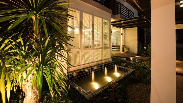 Un espacio exterior moderno con piscina, plantas en macetas y un edificio con ventanas amplias.
