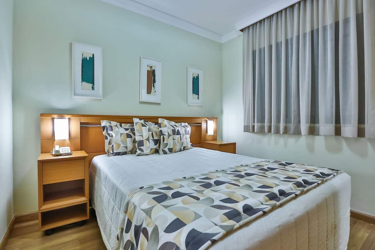 Ein Hotelzimmer mit Bett, Nachttischen, Telefon und Bildern an der Wand.