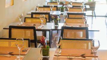 A restaurant with tables set for dining, featuring wicker chairs and a view of the outdoors.