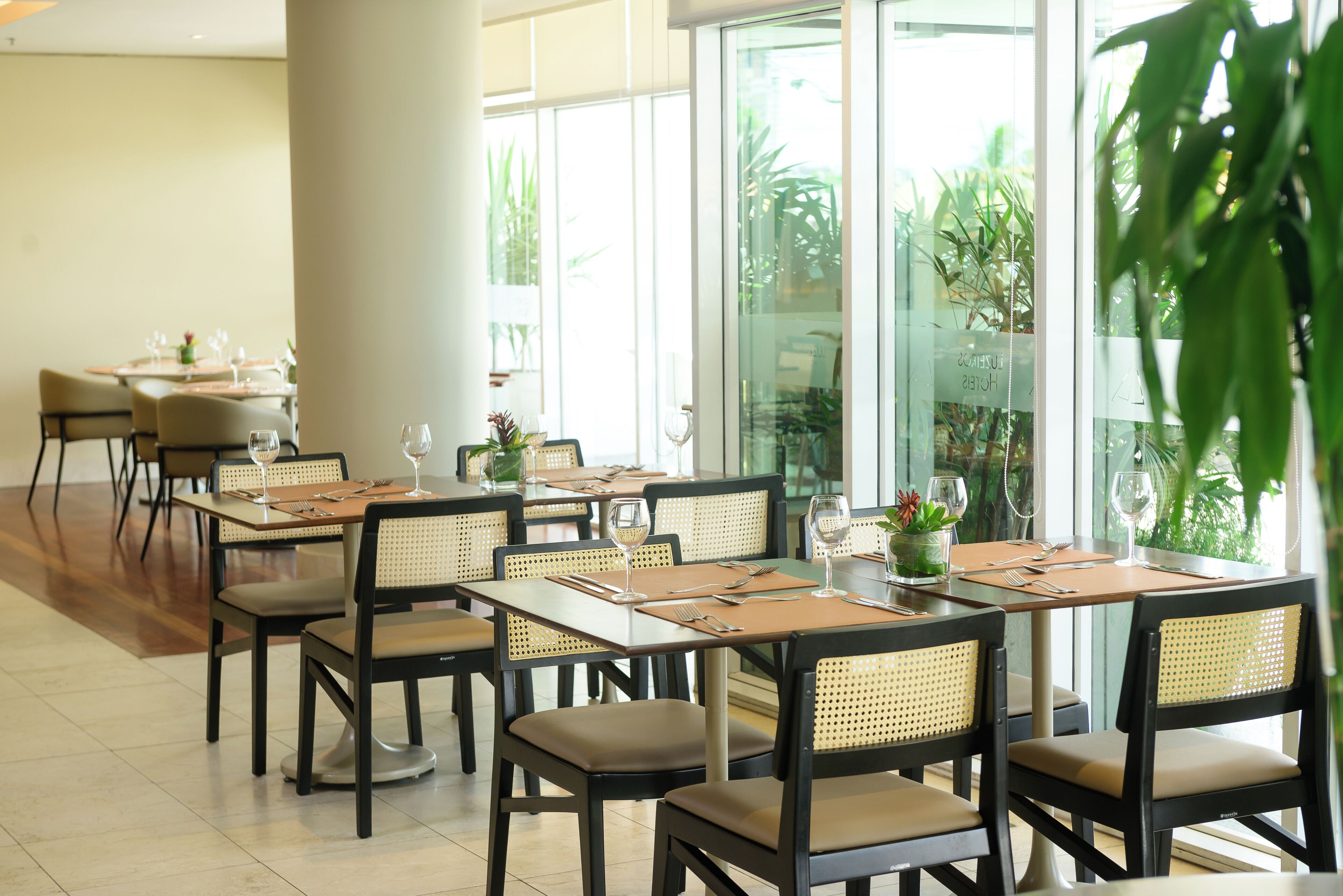 A restaurant with multiple tables and chairs, each set with wine glasses, cutlery, and napkins.