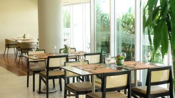 A restaurant with multiple tables and chairs, each set with wine glasses, cutlery, and napkins.