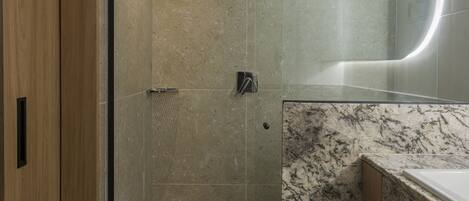 Un baño moderno con cabina de ducha de vidrio, lavabo de mármol y puerta de madera.
