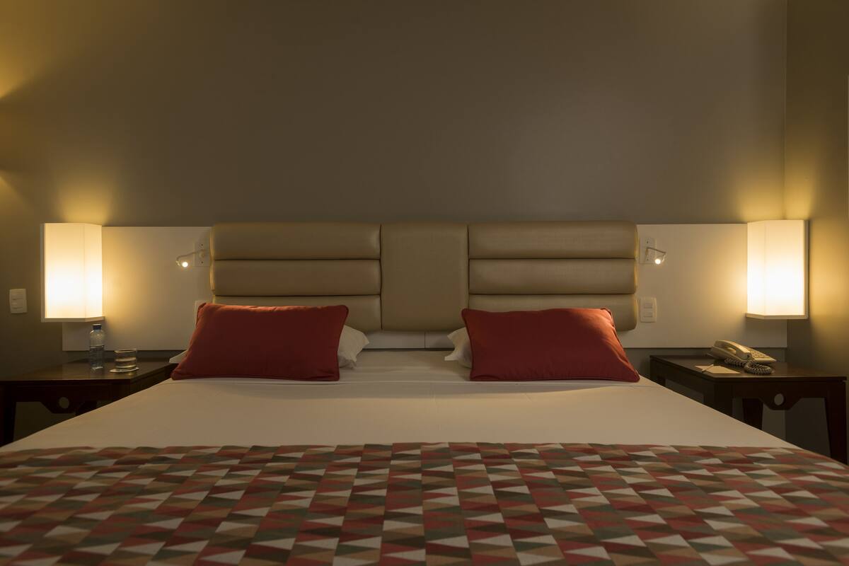 A hotel room with a large bed, two bedside tables with lamps, and a patterned bedspread.