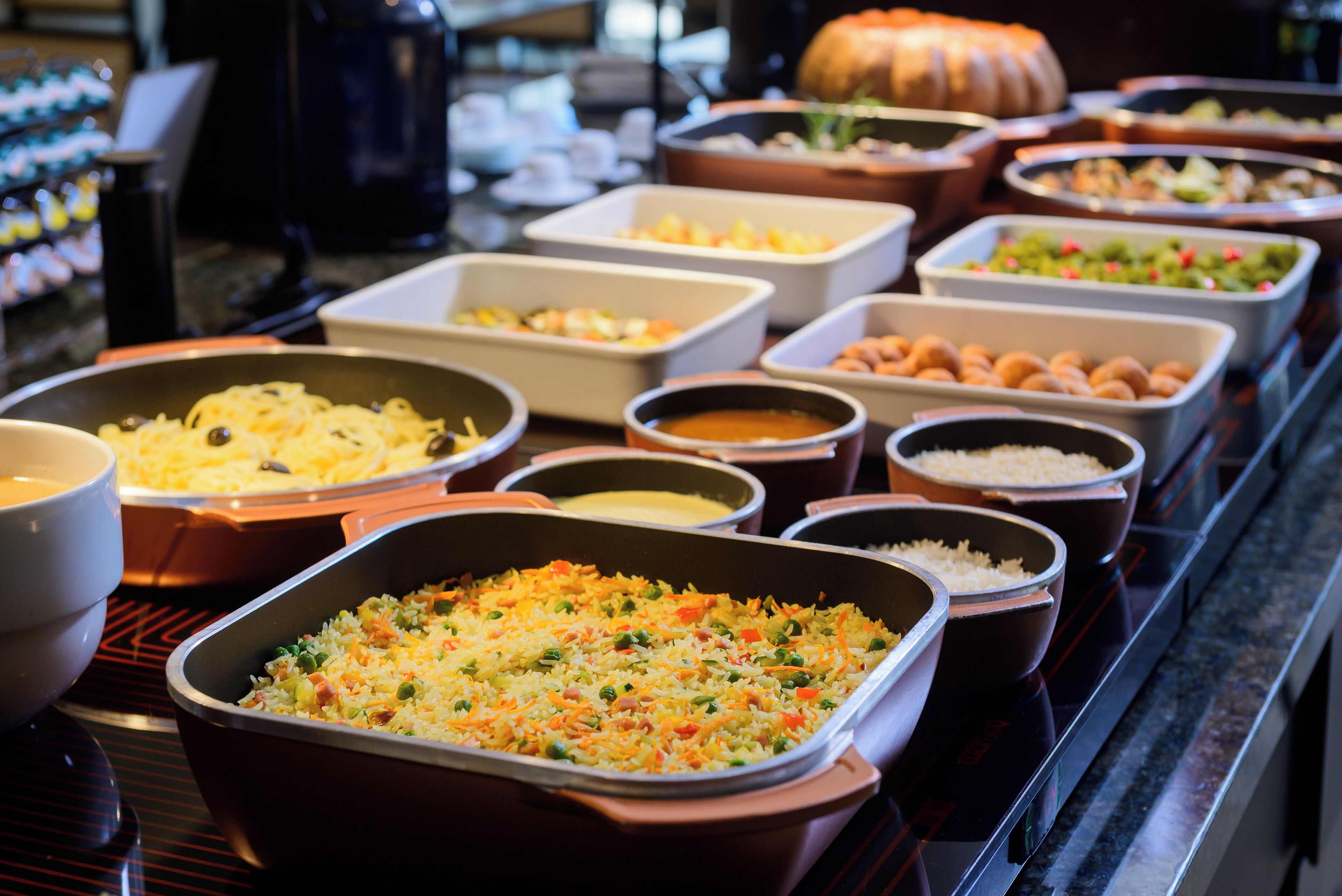 Un bufé con diversos platos, incluyendo arroz, verduras y carne.