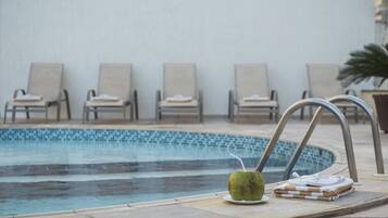 A poolside area with lounge chairs and a coconut drink.