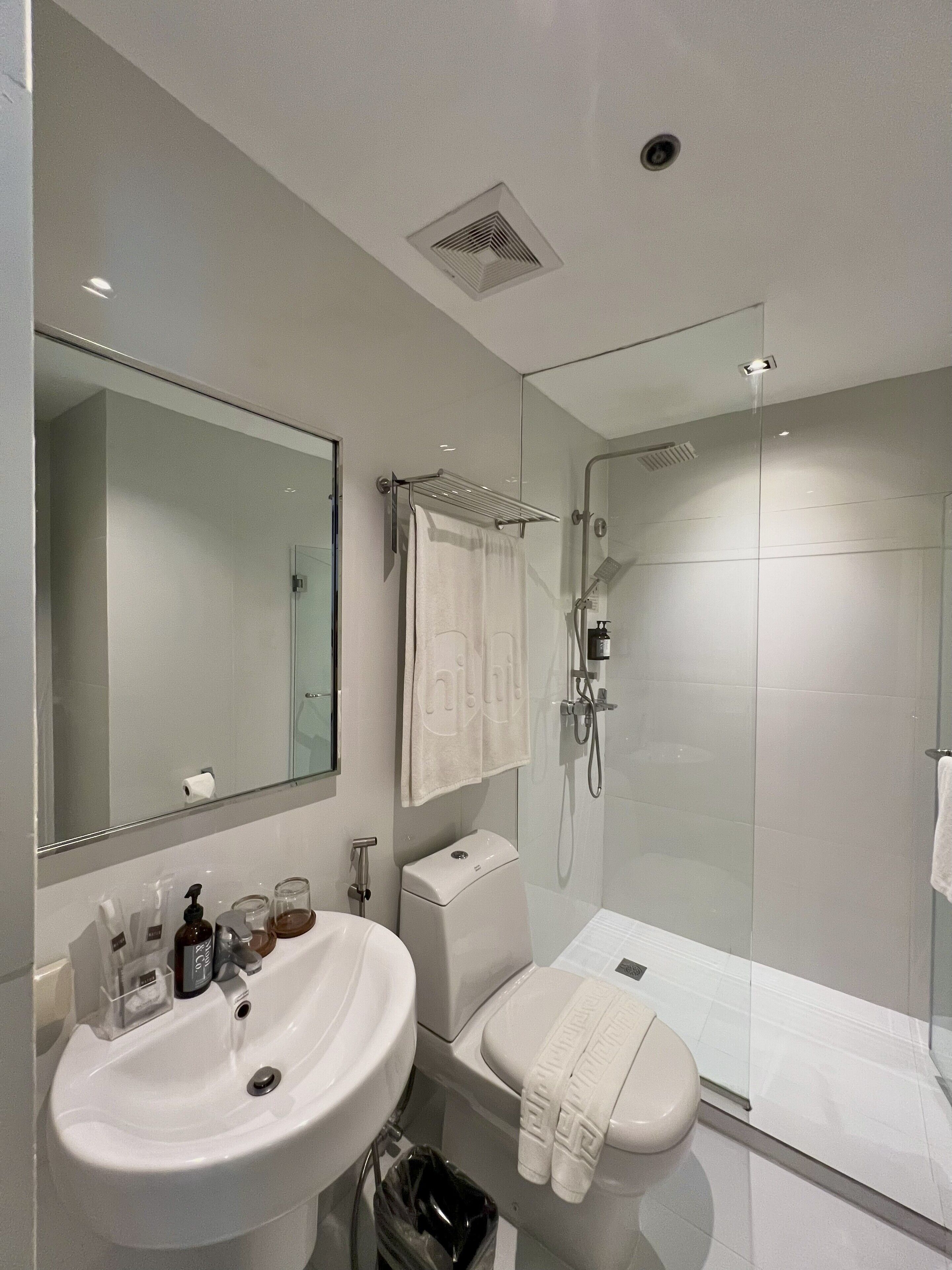 Ein modernes Badezimmer mit großem Spiegel, Waschbecken, Toilette und Duschkabine.