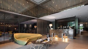 Eine moderne Lobby mit einem gebogenen gelben Sessel, einem Empfangstresen und einer Glastrennwand.