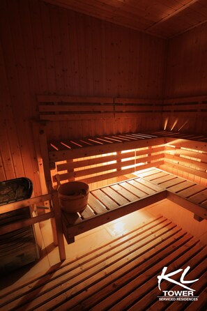 A sauna with wooden benches and a bench with a bucket. - KL Serviced Residences Managed by HII (Makati)