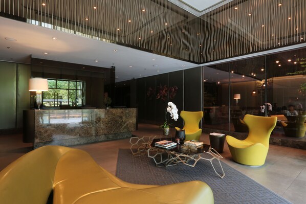 A modern lobby with a reception desk, seating area, and a decorative plant. - KL Serviced Residences Managed by HII (Makati)