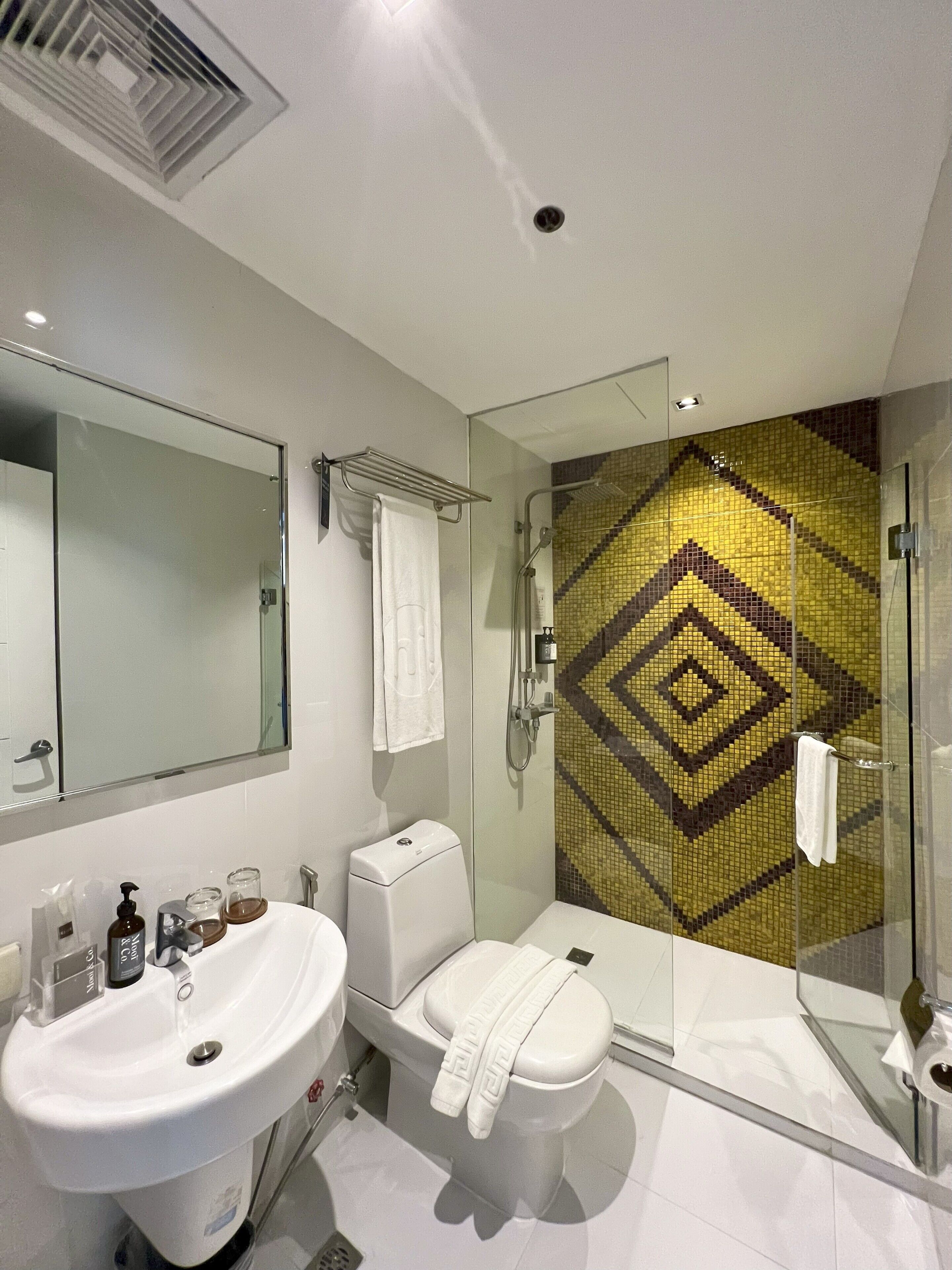 Un baño moderno con cabina de ducha de vidrio, lavamanos blanco y retrete.