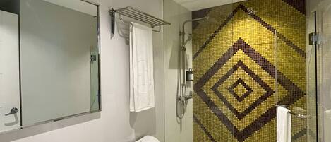 Un baño moderno con cabina de ducha de vidrio, lavamanos blanco y retrete.