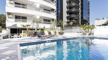 Una piscina al aire libre, sillones reclinables de piscina
