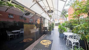 Ein Terrassenbereich im Freien mit Empfangsschild, Sitzmöbeln und Blumentöpfen.