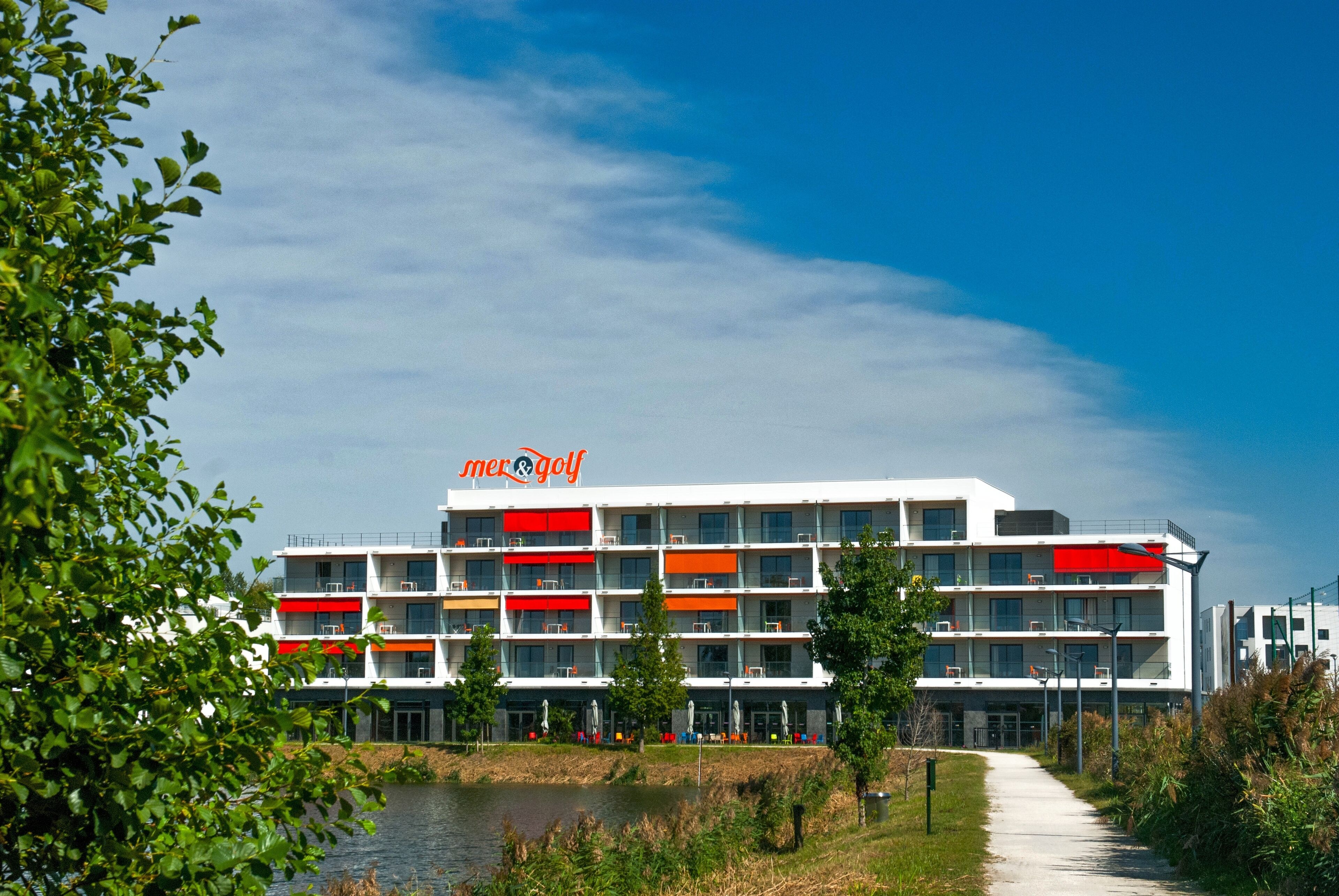 Un hôtel à plusieurs étages au design moderne, doté de balcons et caractérisé par une combinaison de couleurs rouge et blanc très visible.