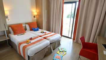 Two beds with matching bedding, a wardrobe, and desk with chair.