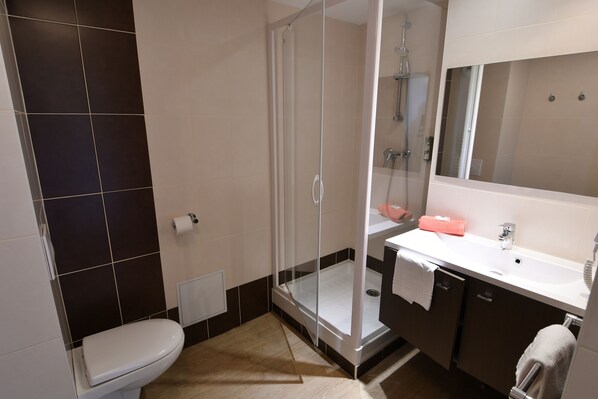Une salle de bain moderne avec une douche à parois de verre, un lavabo blanc et un grand miroir.