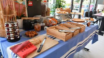 A buffet table with various food items, including bread, pastries, and condiments.