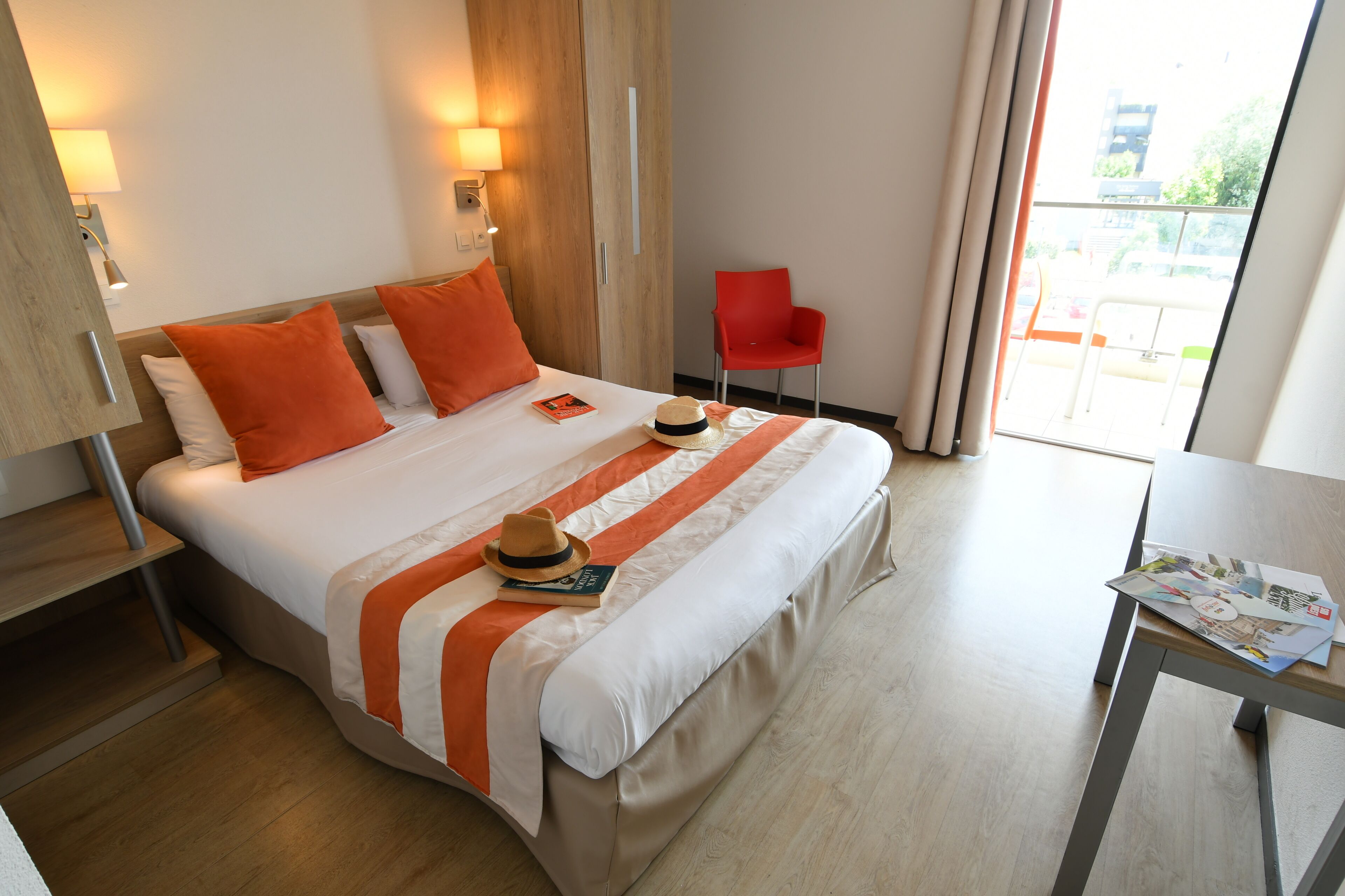 Une chambre d’hôtel avec un lit, une chaise, une table et une fenêtre.