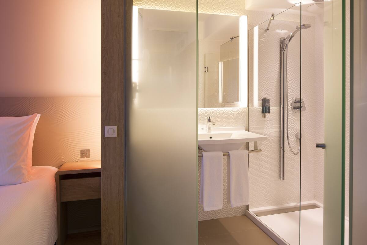 Un baño moderno con cabina de ducha de vidrio, un lavabo blanco y un espejo sobre él.