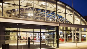 Un bâtiment moderne doté d’une façade en verre et d’une structure de toit incurvée.