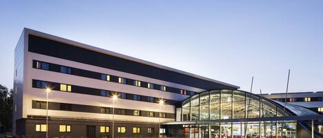 A modern building with a curved glass entrance and multiple floors.