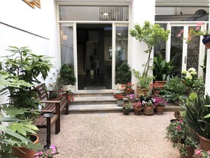 A courtyard with a variety of potted plants and a wooden bench. - Hostal Mediterráneo (Tossa de Mar)