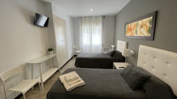 A hotel room with two beds, a desk, a chair, a TV, and a painting.