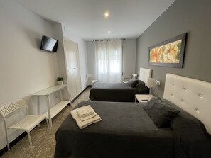 A hotel room with two beds, a desk, a chair, a TV, and a painting.