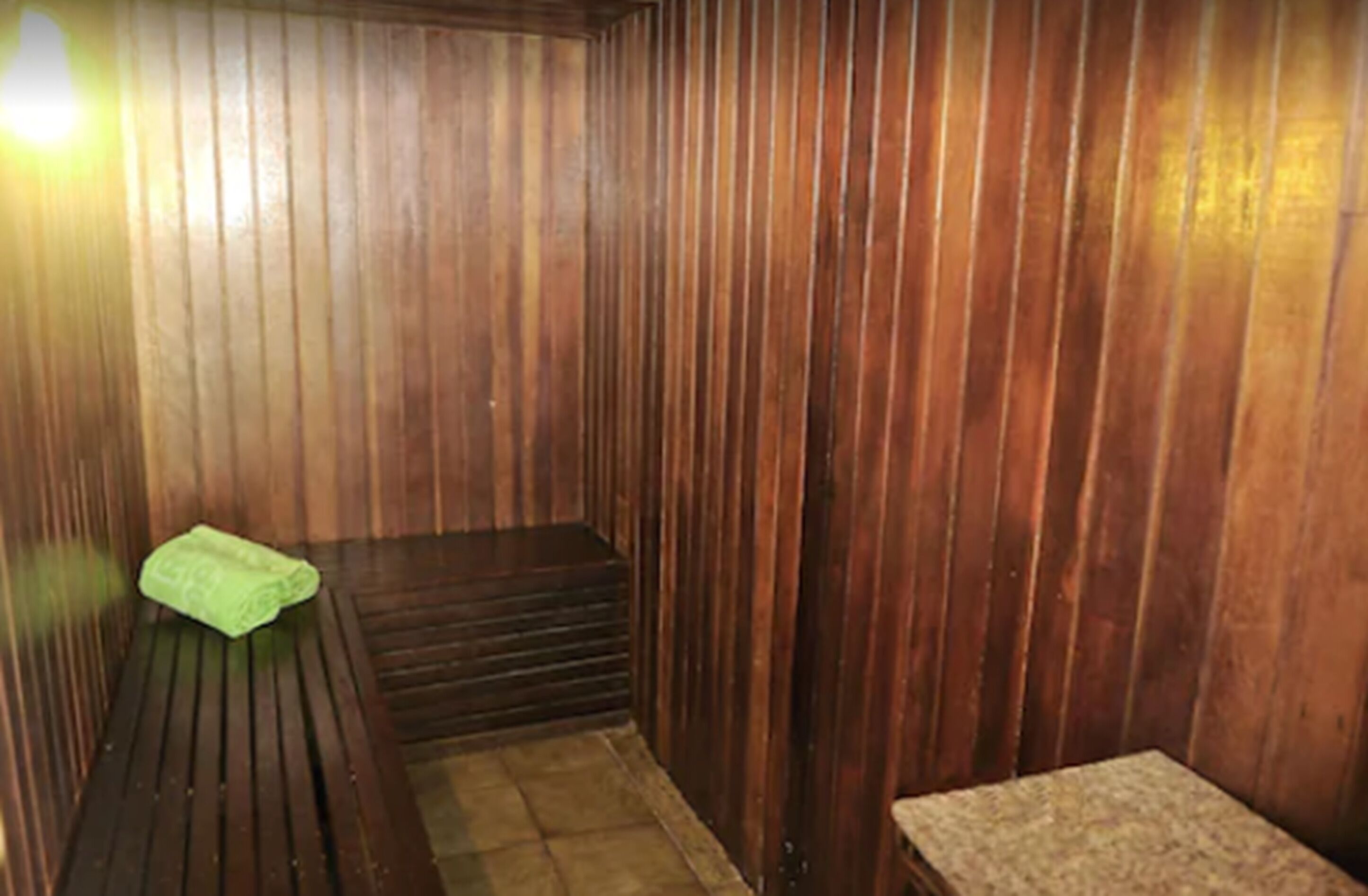A wooden sauna room with benches and a bench with a towel.