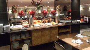 Ein Bereich mit Buffet, verschiedenen Speisen, einer Kaffeestation und einer Sitzecke mit Tischen und Stühlen.