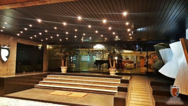 Eine Hotelhalle mit einer prunkvollen Treppe, einer Rezeption und einer Chandelier.
