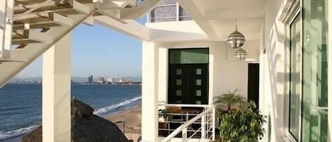 A balcony with a view of the ocean, a staircase, and a door.