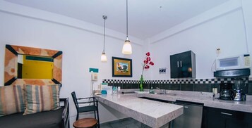 Una cocina moderna con encimera de mármol, armarios negros y microondas integrado.