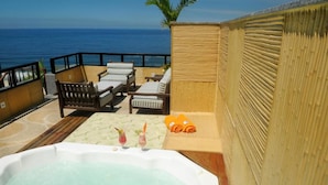 Une terrasse sur le toit avec un jacuzzi, des chaises longues et une vue sur l’océan.