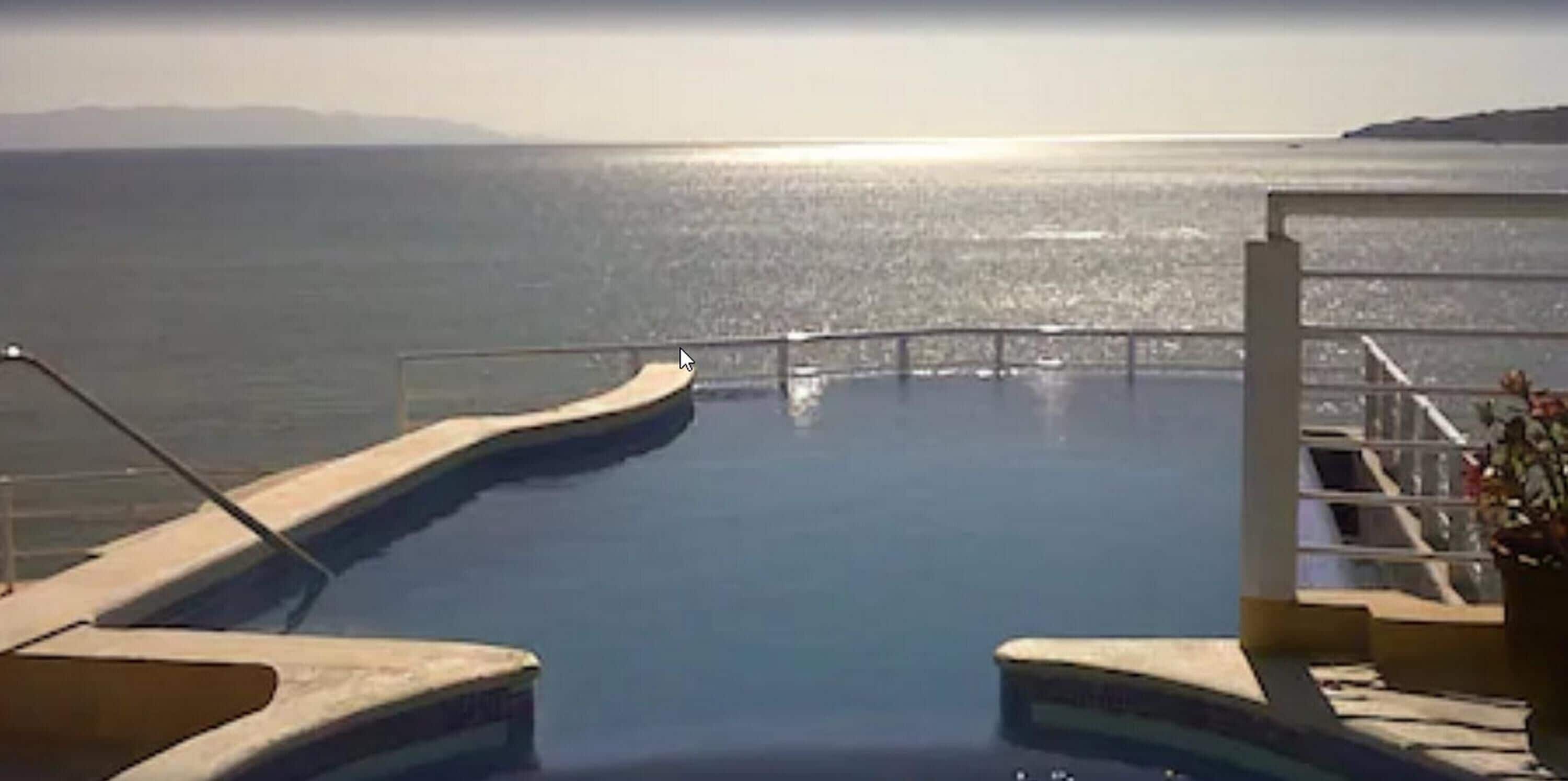 Ein Infinity-Pool mit freiem Blick auf das Meer und die entfernten Berge.