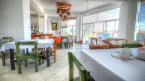 A dining area with tables and chairs, a sofa, and a view of the outside. - Hotel Boutique Suites Nadia Bucerias (Bucerías)