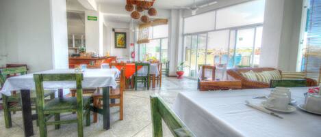 A dining area with tables and chairs, a sofa, and a view of the outside.