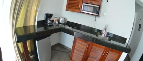 A compact kitchen with a microwave, a coffee maker, and a small refrigerator.
