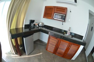 Una cocina compacta con microondas, cafetera y refrigerador pequeño.