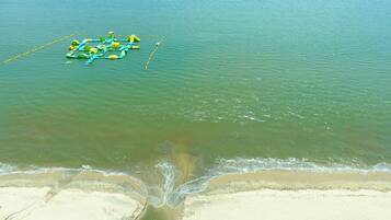 A beach with clear water and a floating structure with green and yellow elements.
