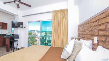 Habitación de hotel con cama, escritorio, televisión y vistas de la ciudad.
