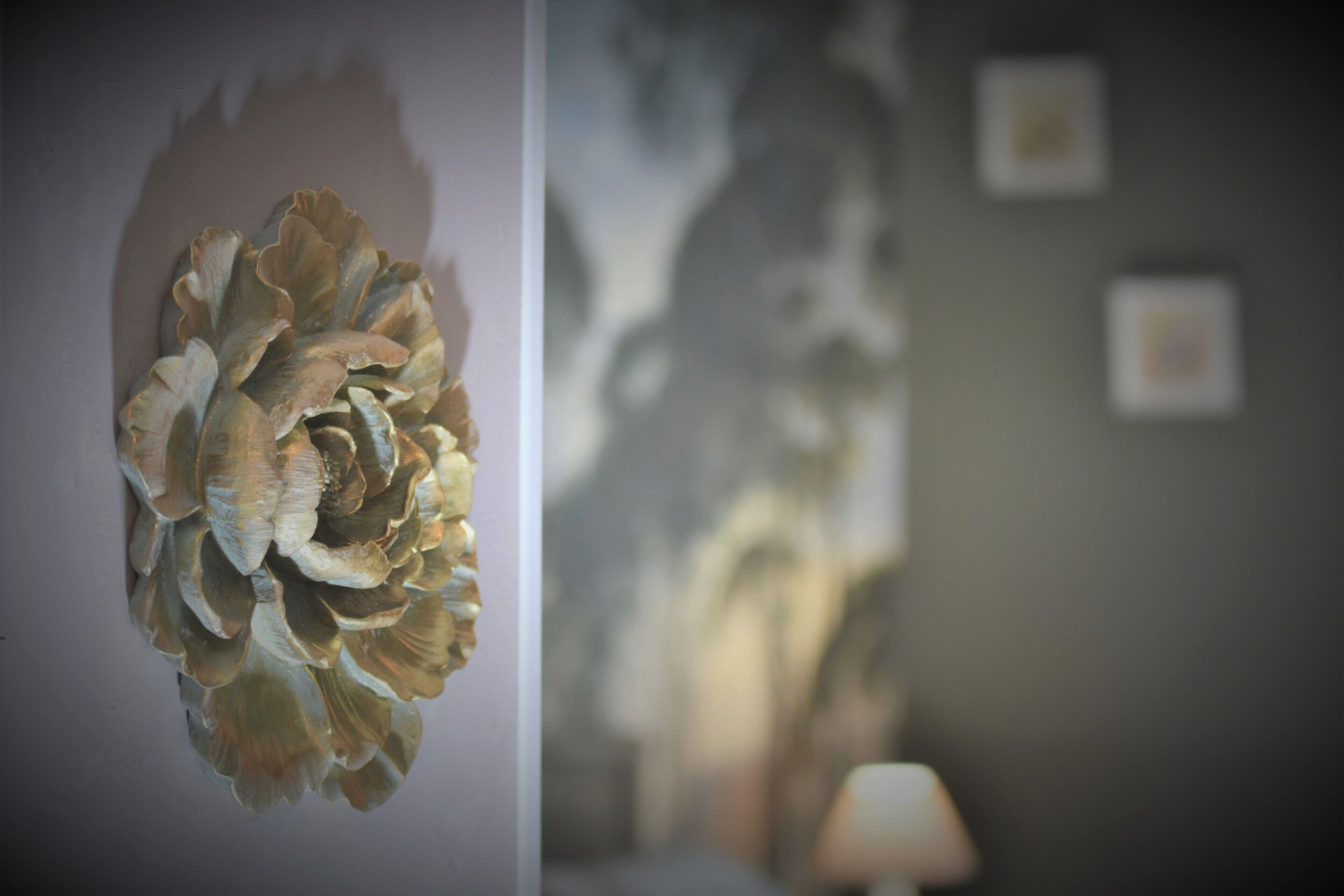 Un mur orné d’une œuvre d’art florale à motifs et sur lequel se trouve, en arrière-plan, une série de tableaux encadrés dont les contours sont flous.