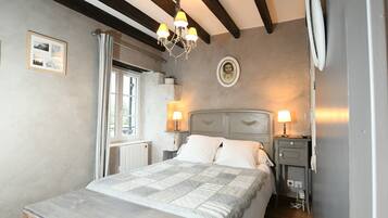 Une chambre à coucher avec un lit, des lampes de chevet, une table de chevet, une fenêtre et un lustre.